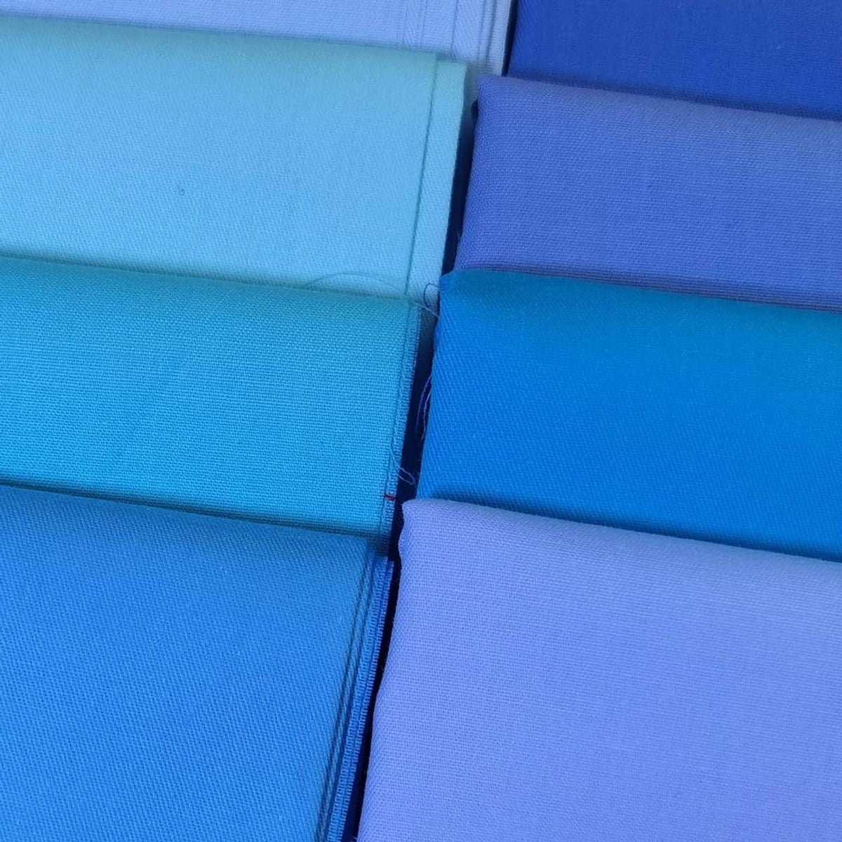 Close-up of stacked solid cotton fabric pieces with visible seams and folds