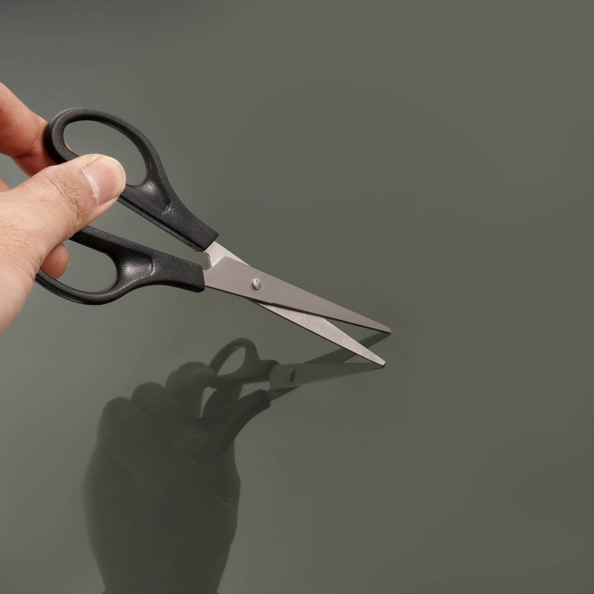 Hand using black scissors to cut screen trim along the edge of an RV window frame