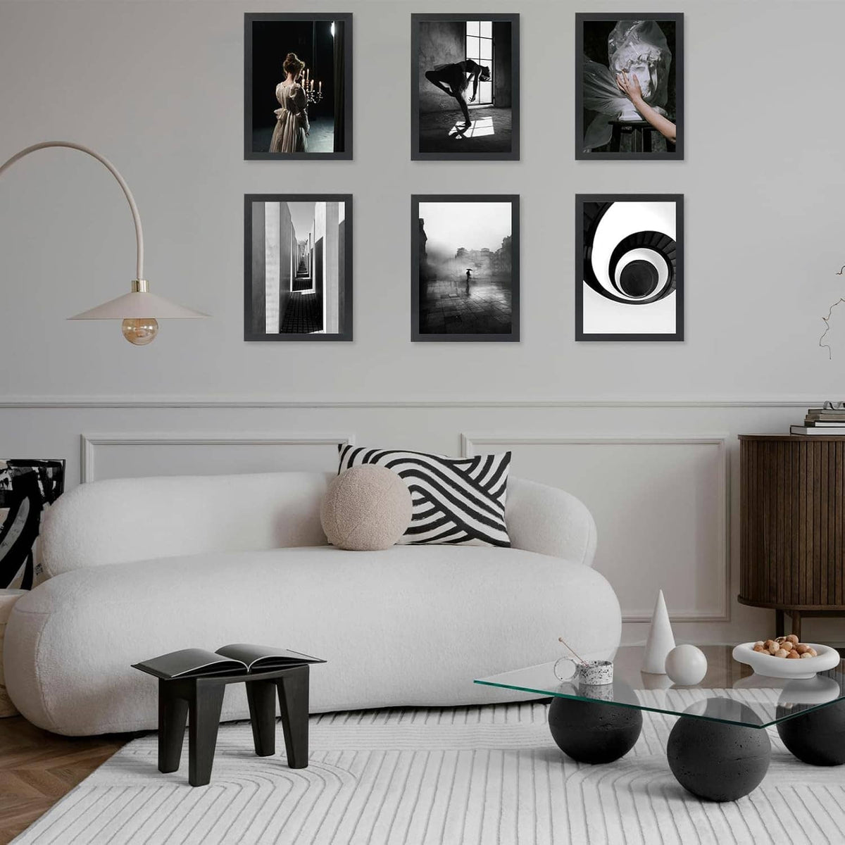 Set of black 10x15 picture frames on a wall above a sofa with multiple photos.