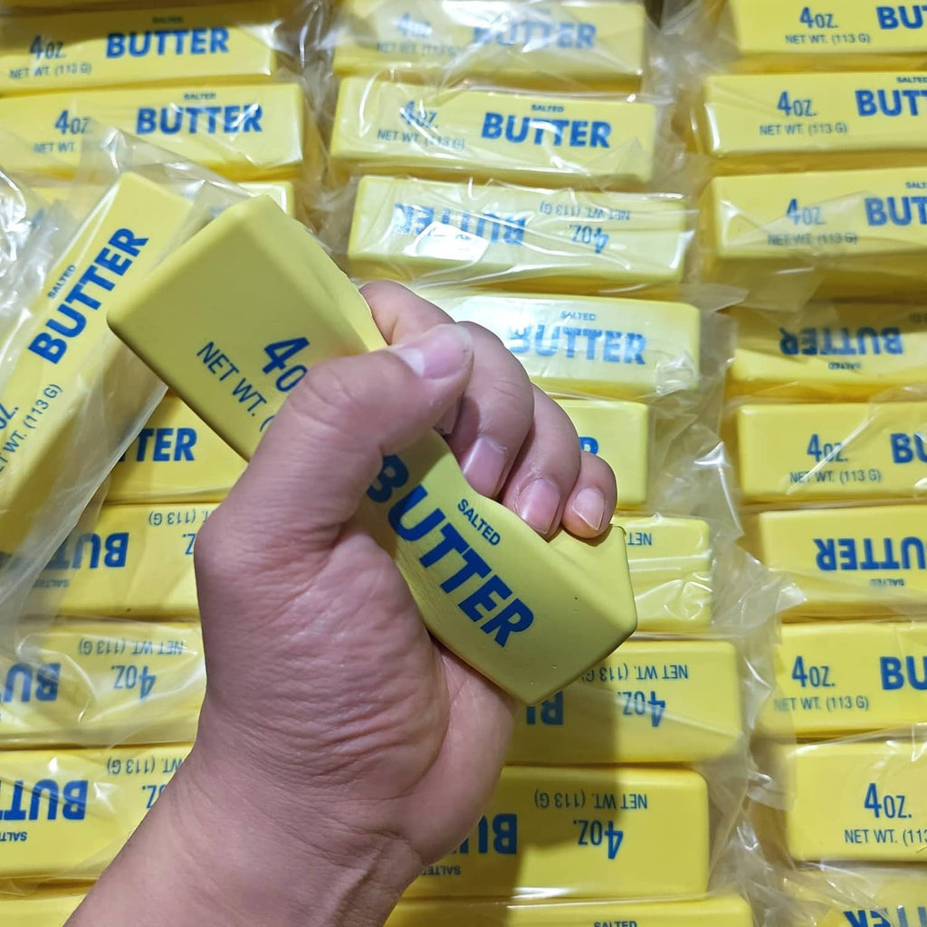 Hand squeezing a yellow salted butter squishy fidget toy among wrapped bars