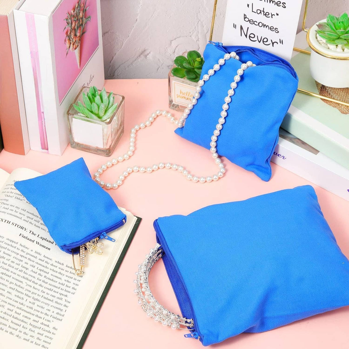 Blue zipper jewelry storage pouches with pearl strands and bracelets arranged on book