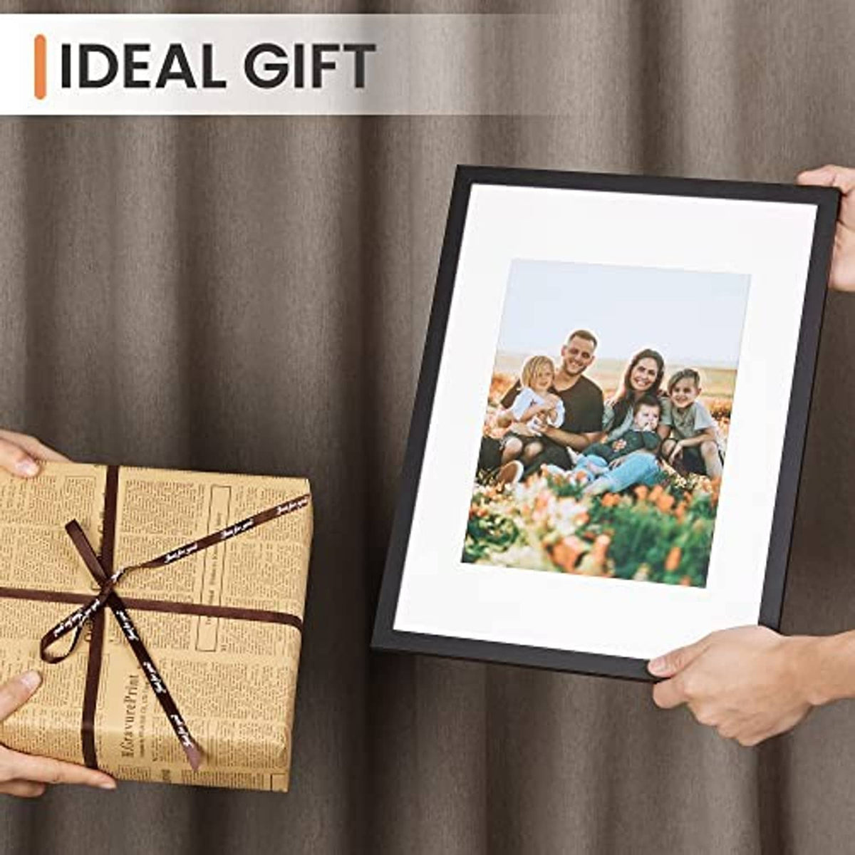 Black picture frame holding a color family portrait, shown held by two hands