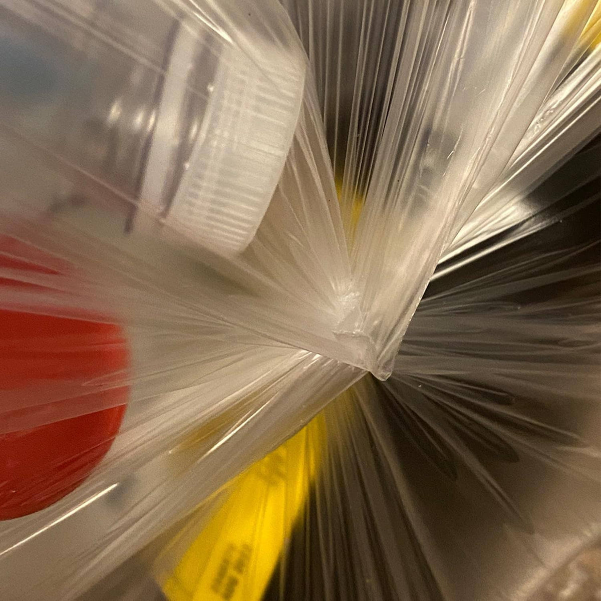 Clear trash bag liner tied at the top, tightly gathered plastic