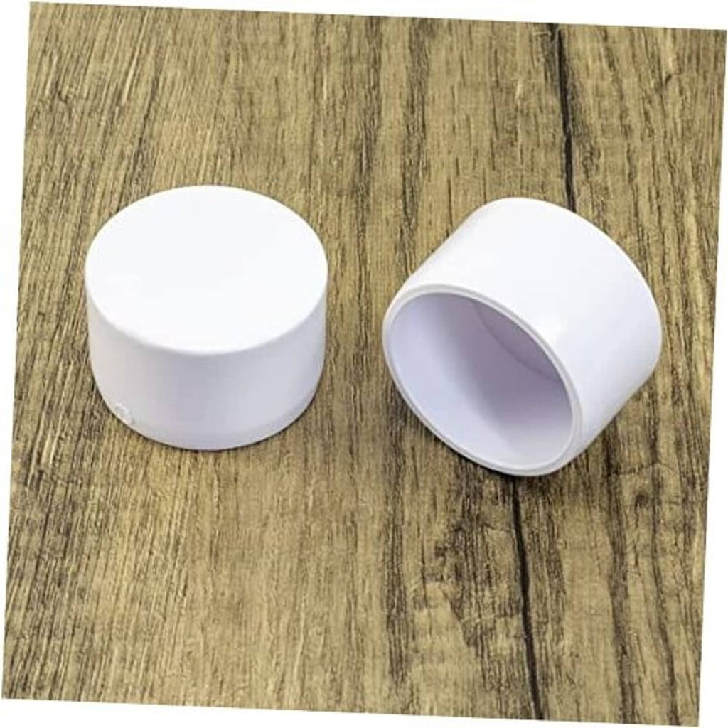 White 1-1/4 in PVC pipe end cap plug pair, one angled and one top view