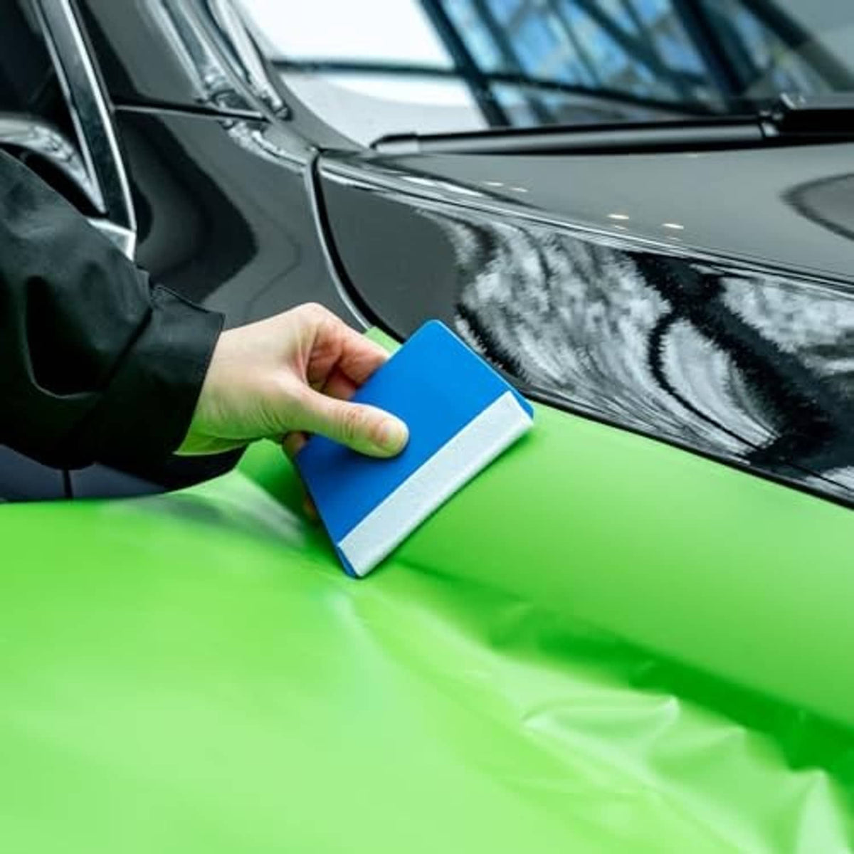 Using a blue vinyl card to smooth a car surface film