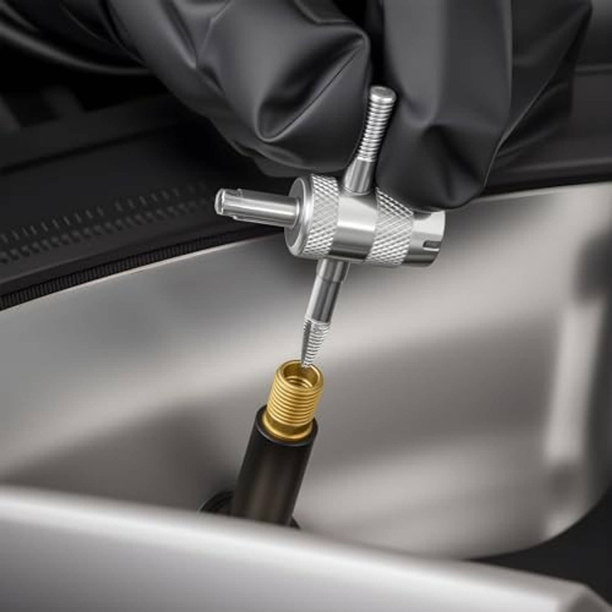 Silver valve core tool installing on a tire valve in a glove