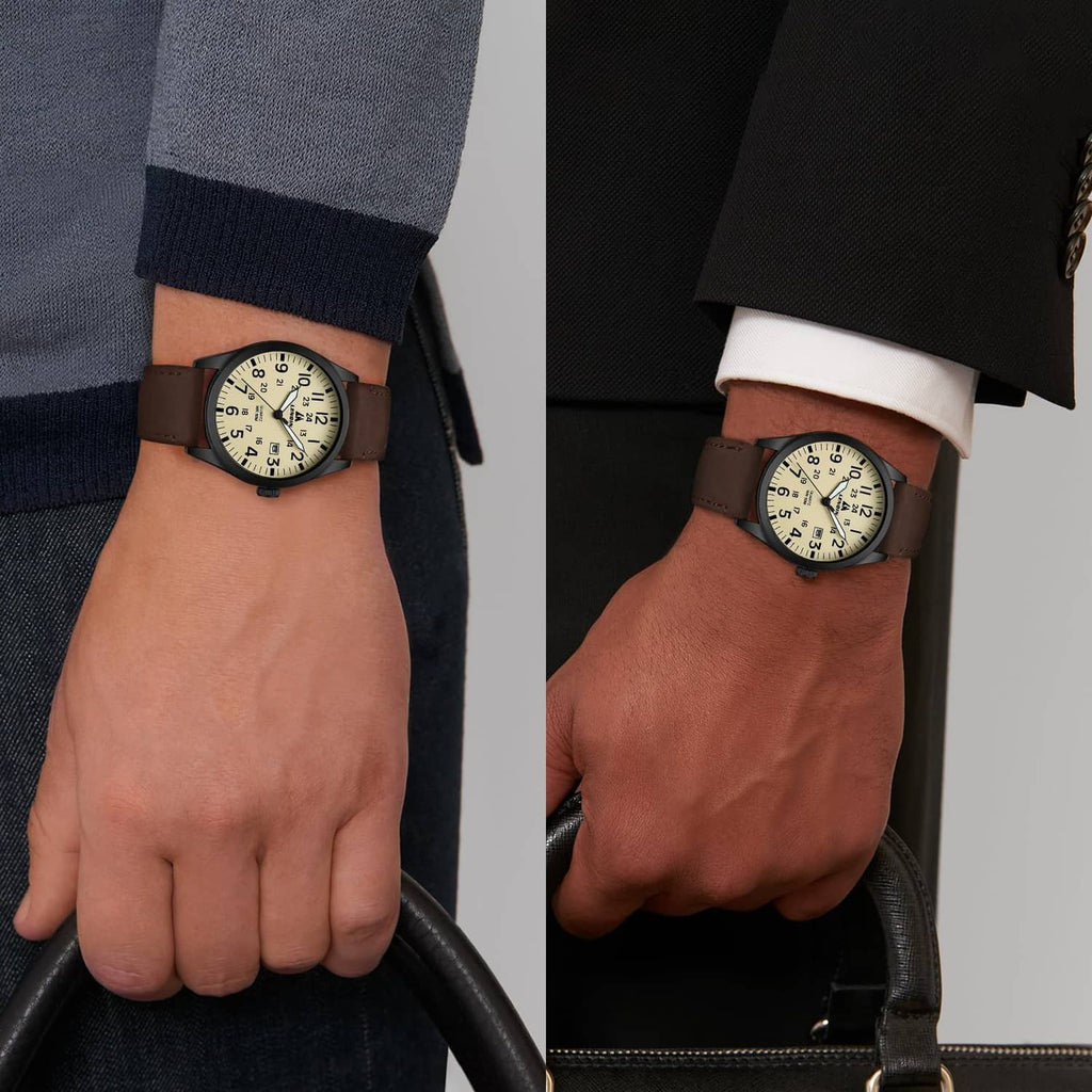 Men's analog watch worn on wrist with brown leather strap and beige dial, paired with dark sleeves.