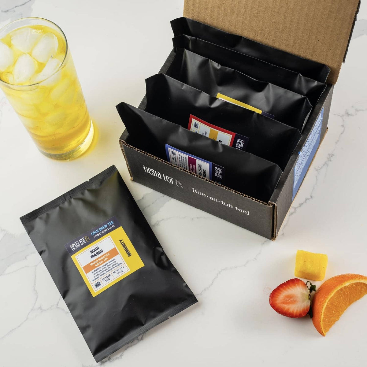Opened cardboard box containing Tiesta Tea cold brew tea packets and brewed drink