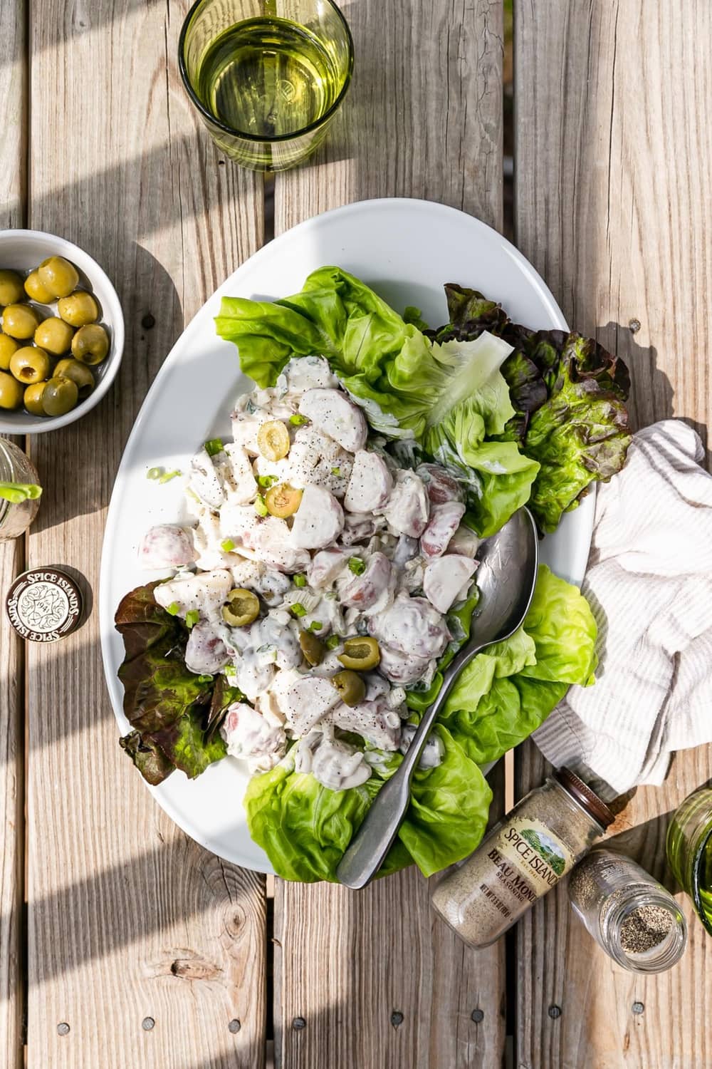 Plate of salad with seasoning-coated pieces and small spice jars on a table