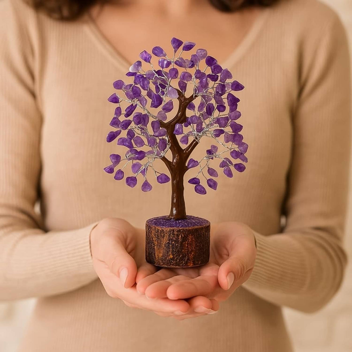 Amethyst crystal tree decoration held in hands, purple gem leaves on round wooden base