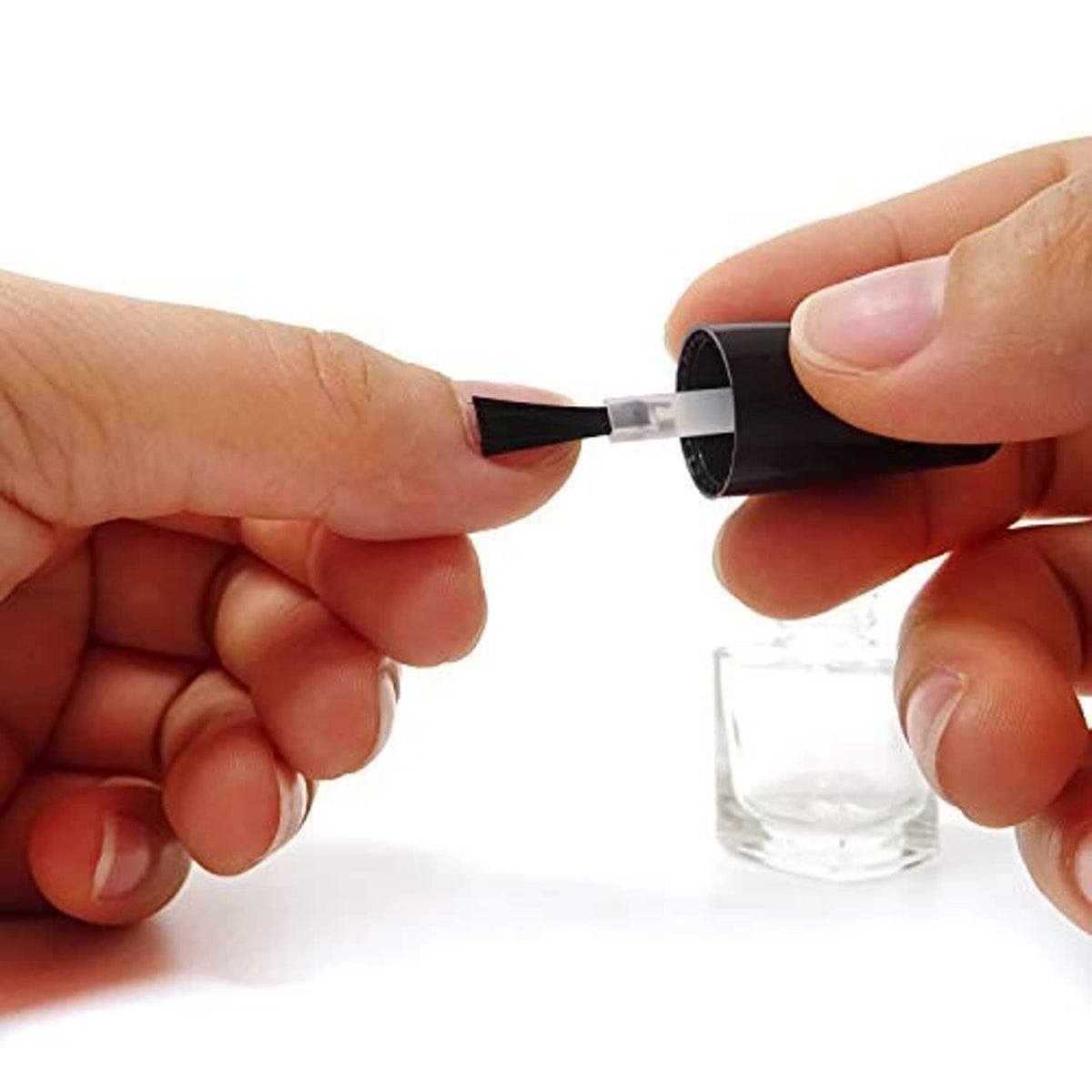 Hand inserting a brush into a black-capped clear nail polish bottle