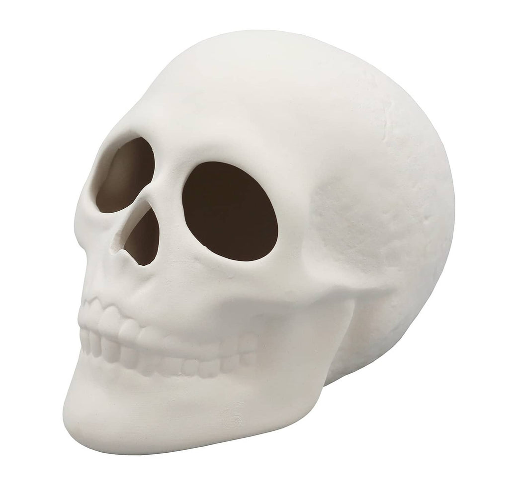 White ceramic bisque skull figurine, side view with dark eye opening and teeth
