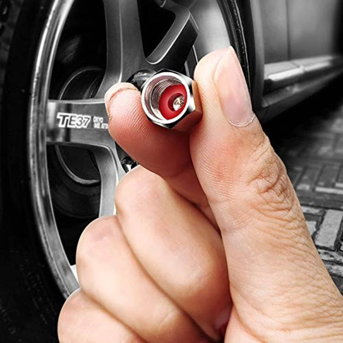 Hand installing chrome tire valve stem cap with red insert onto a wheel valve