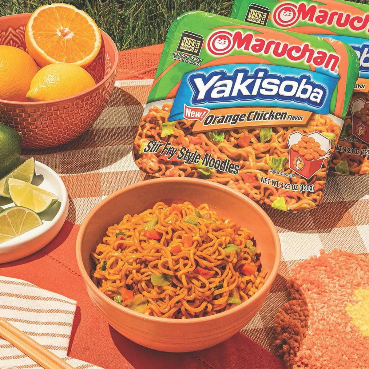 Orange chicken Yakisoba noodles in a bowl with seasoning pack and orange garnish