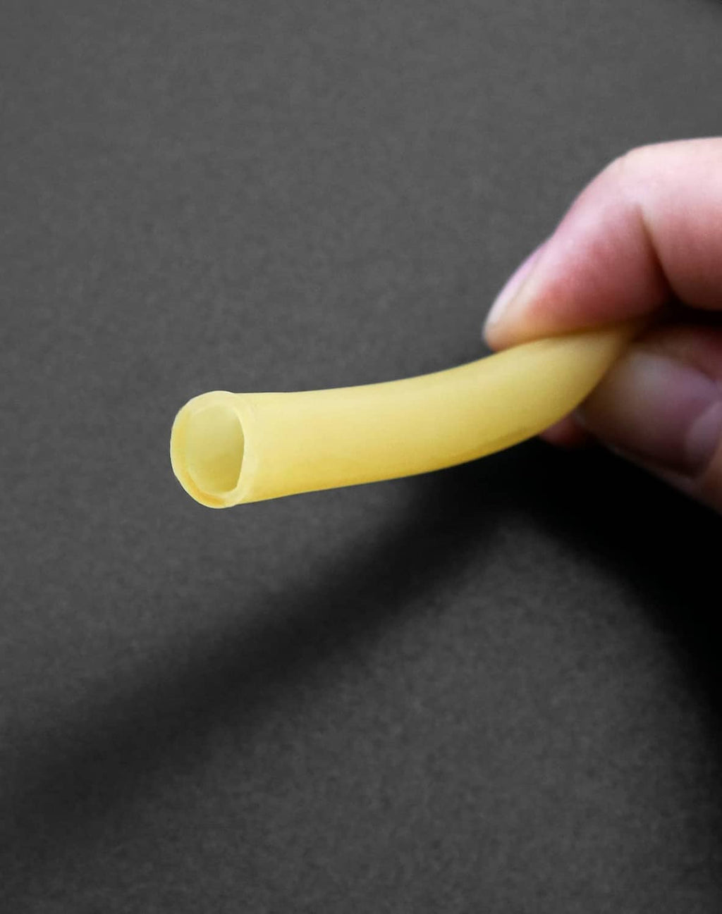 Natural latex rubber tubing, yellow end with inner opening held by hand