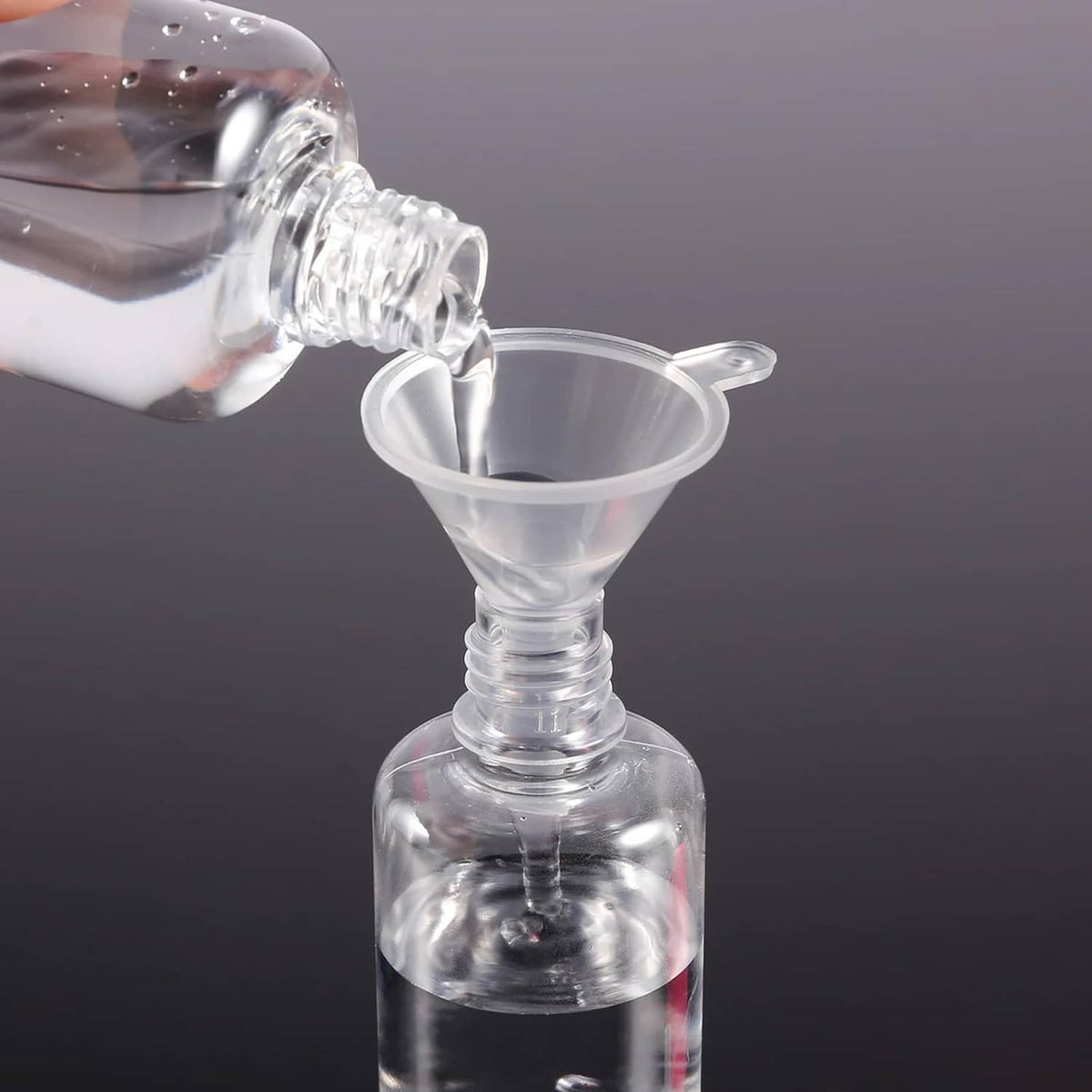 Perfume funnel extractor pouring into bottle with clear plastic transfer tool