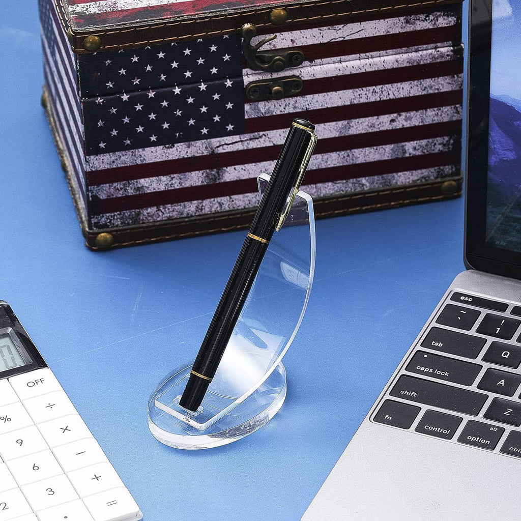 Clear acrylic pen holder with black and gold pen, set on tabletop