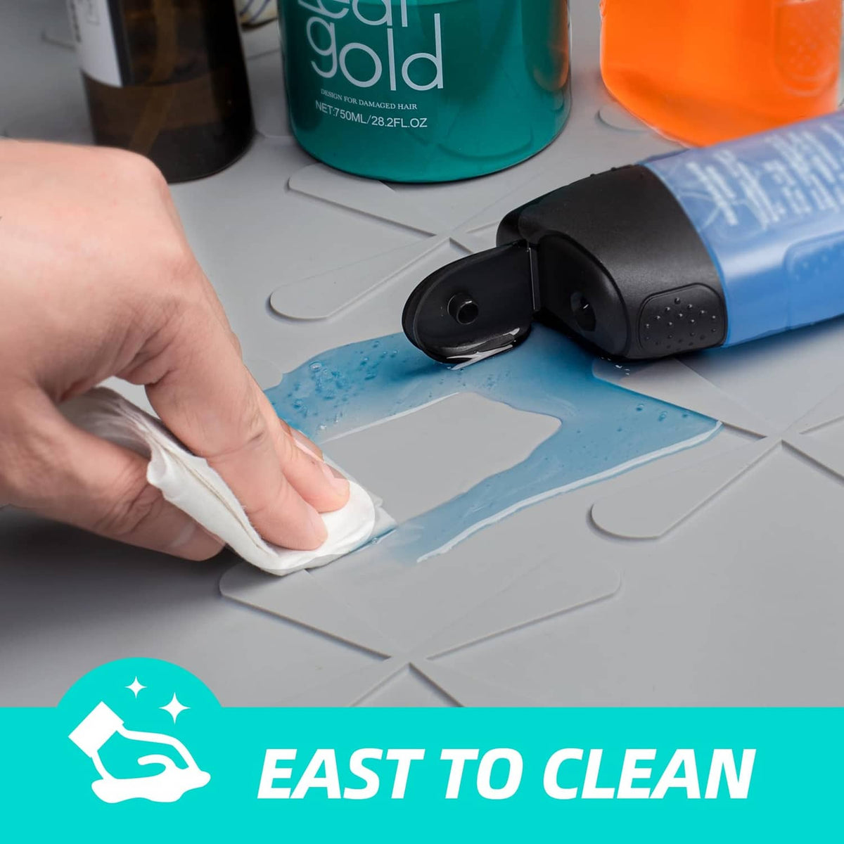 Gray silicone under-sink mat being wiped clean with a sponge; water-resistant surface