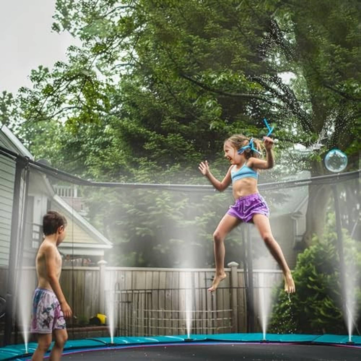 Outdoor misting system releasing a fine water spray from overhead hose nozzles