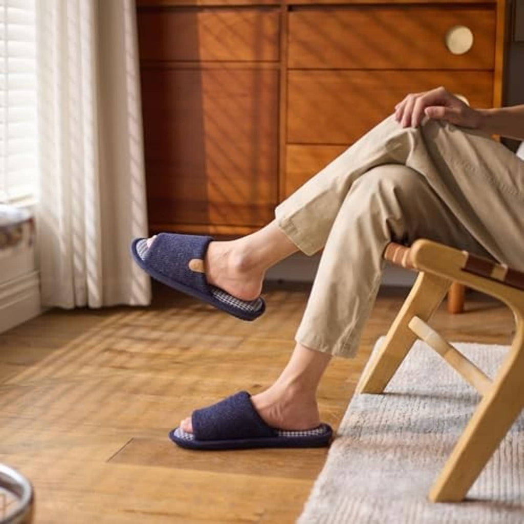 Men's navy memory foam slippers on feet indoors, plaid lining visible at openings