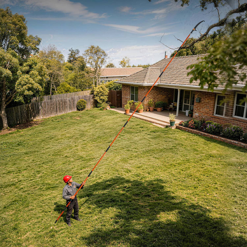Extendable pole saw pruner with orange pole cutting high branches over lawn