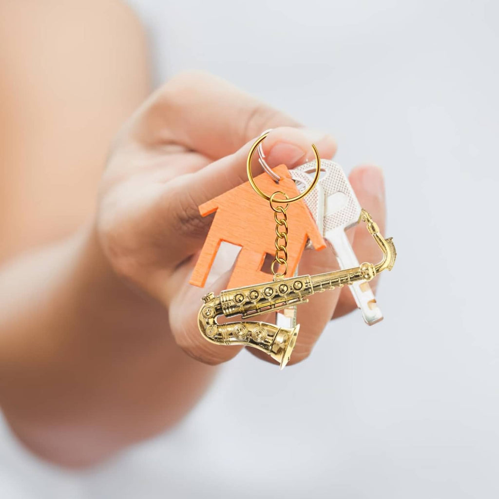 Gold mini saxophone keychain model held in a hand