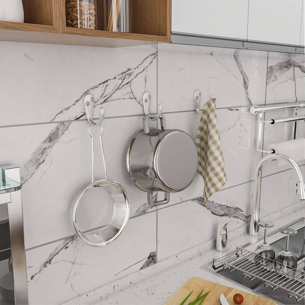 Wall-mounted single-prong coat hooks holding kitchen pans and cloth, silver