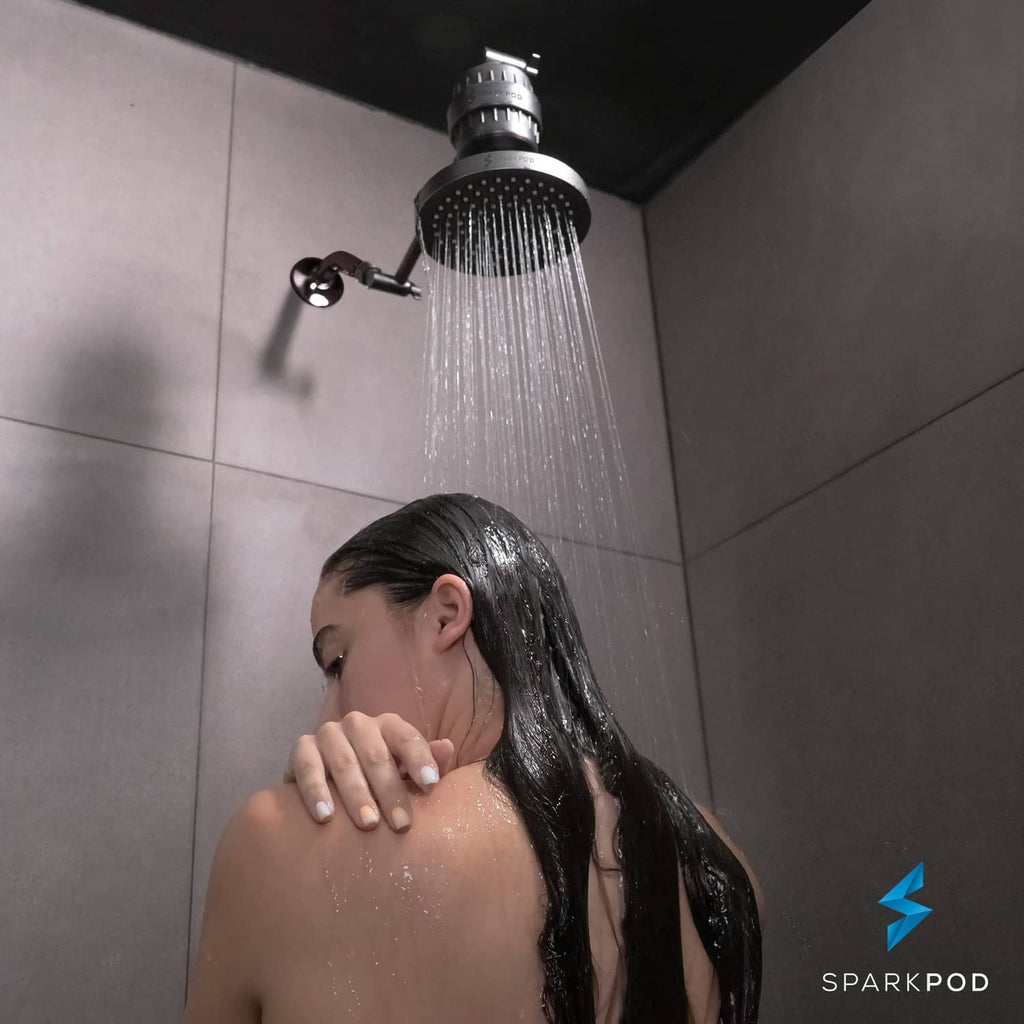 Person under oil rubbed bronze rain shower head with overhead water spray