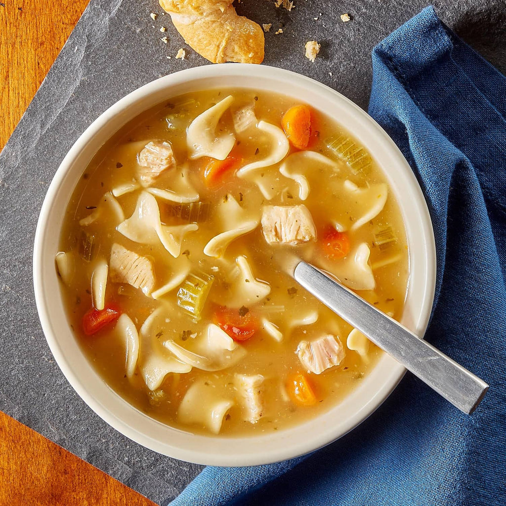 Bowl of chicken noodle soup with visible chicken, carrots, and noodles
