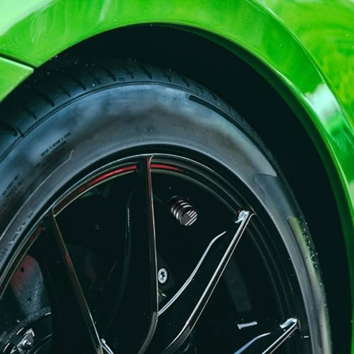 American flag tire valve stem cap installed on a green car tire
