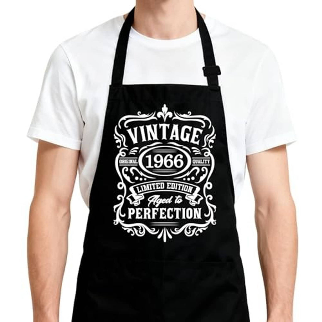 Black kitchen apron with adjustable straps and central vintage 1966 style emblem.