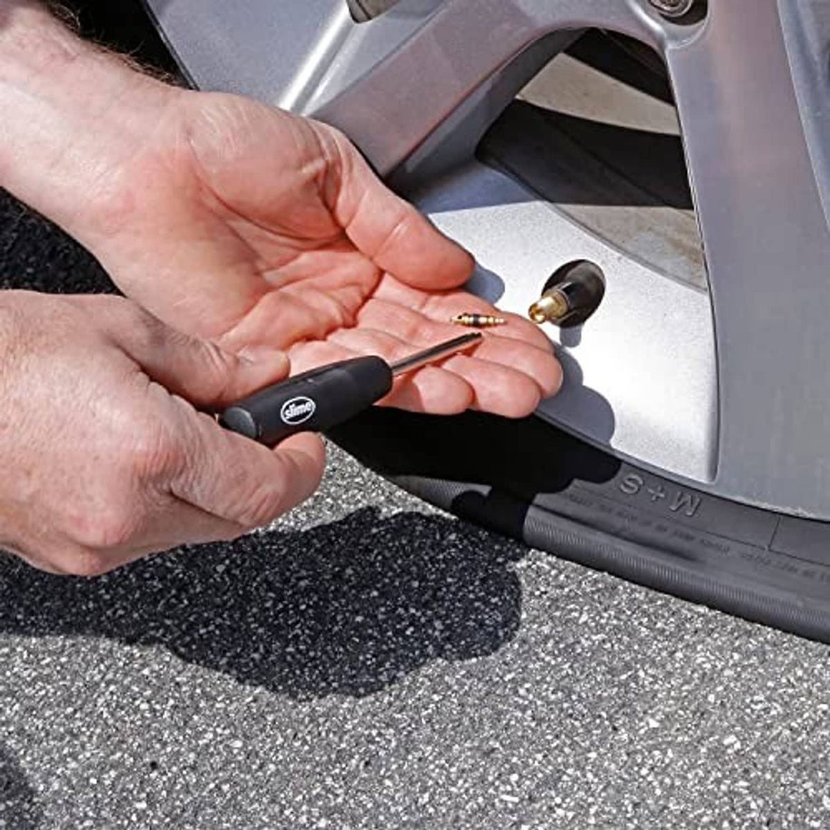 Valve core tool in use: hands using black handle to tighten a valve core