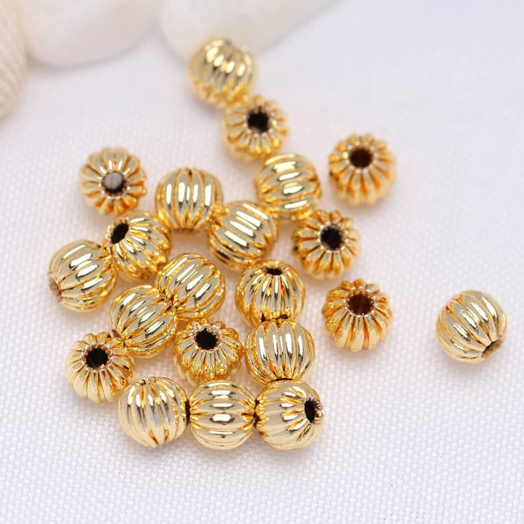 Gold-tone corrugated round beads with black center dots and ridged sides