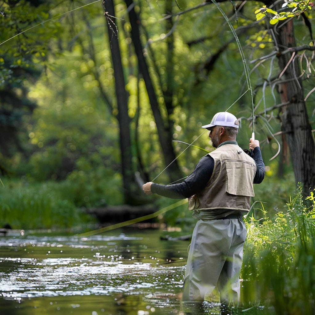 Person fly fishing with a green fly rod and line near the water