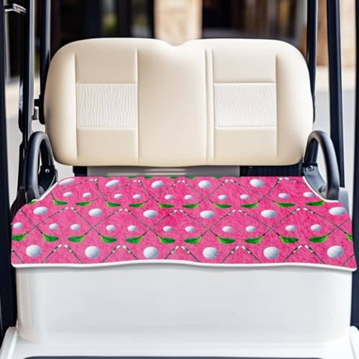 Golf cart seat cover in pink with leaf-and-dot pattern, laid flat on beige bench