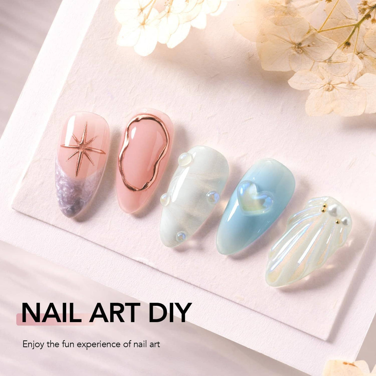 Assorted 3D nail art samples on a card, including rose gold, blue, pearl, and glitter designs