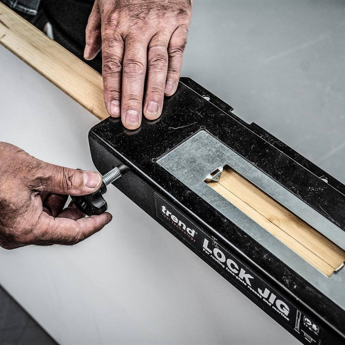 Hands adjusting trend LOCK JIG on a wooden door edge with clamping base