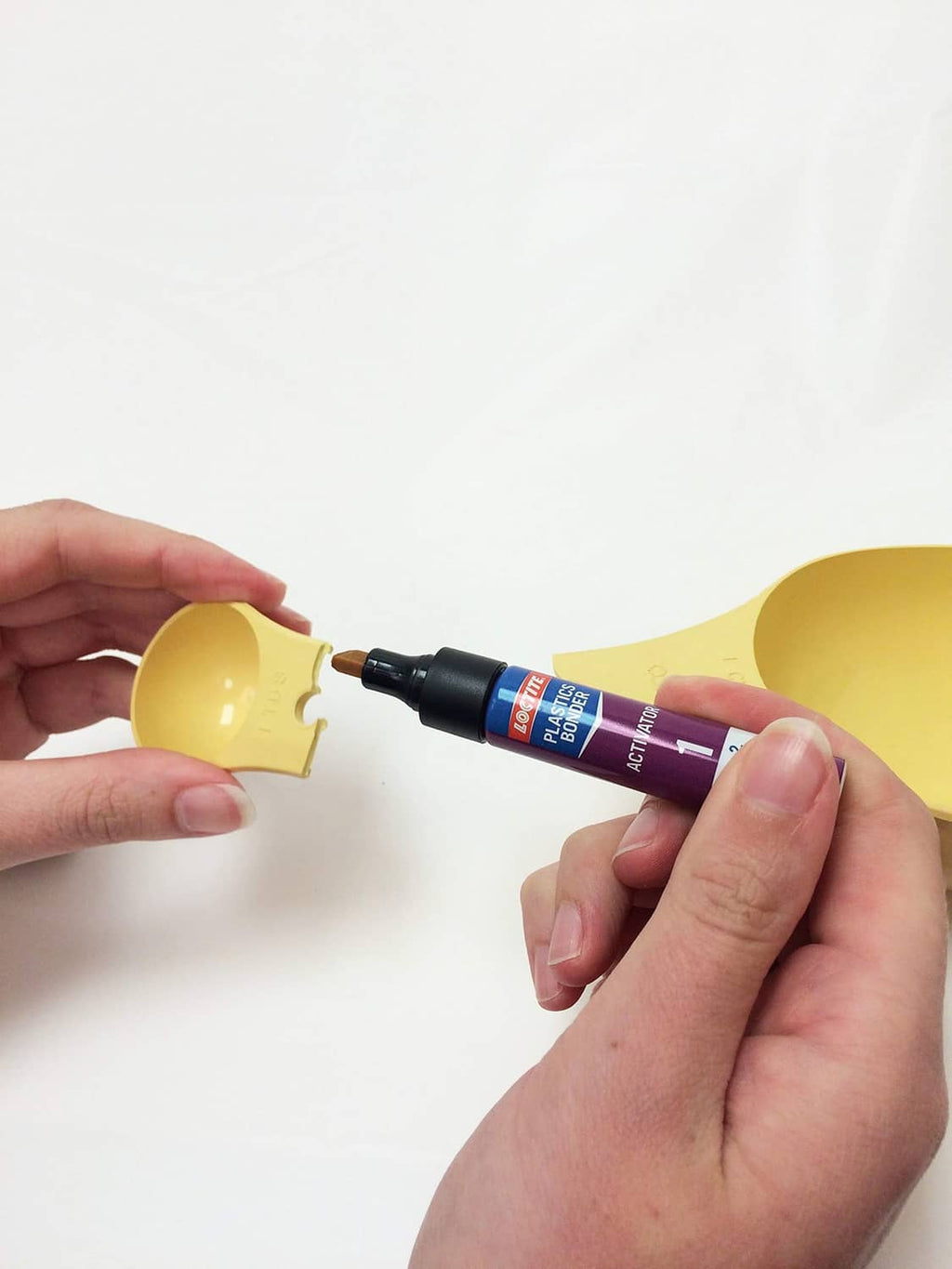 Loctite Plastics activator applicator applying glue to a yellow plastic piece