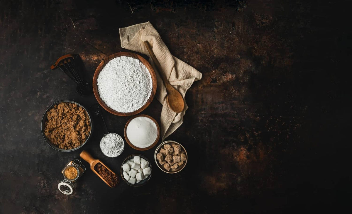 Dark muscovado sugar granules in bowls with white powder
