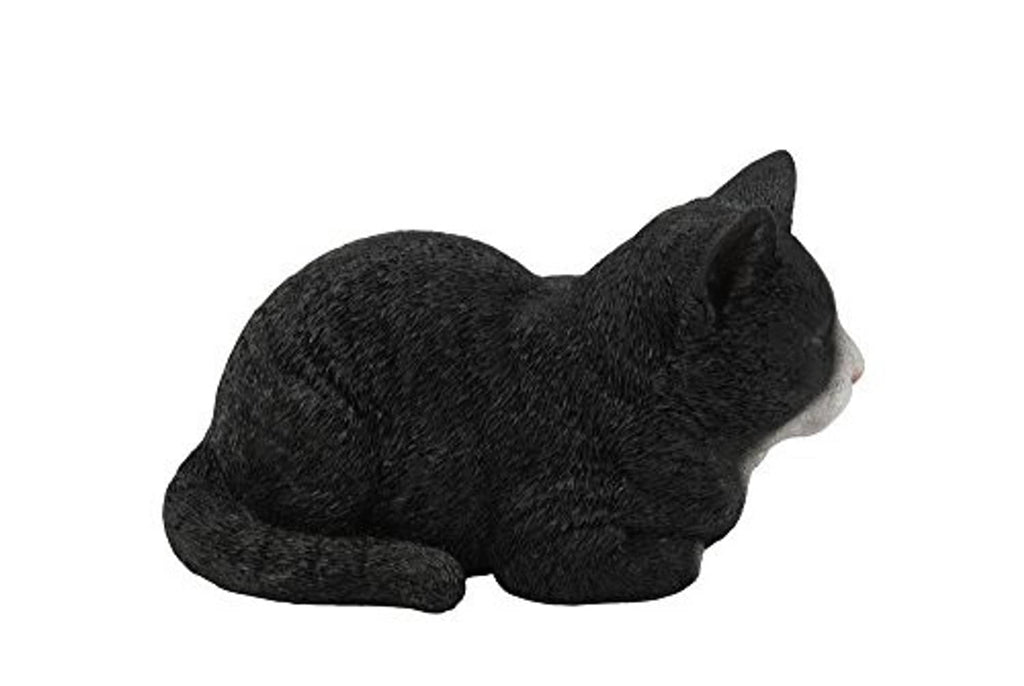 Sleeping cat statue, black with small white paw, lying curled with head up