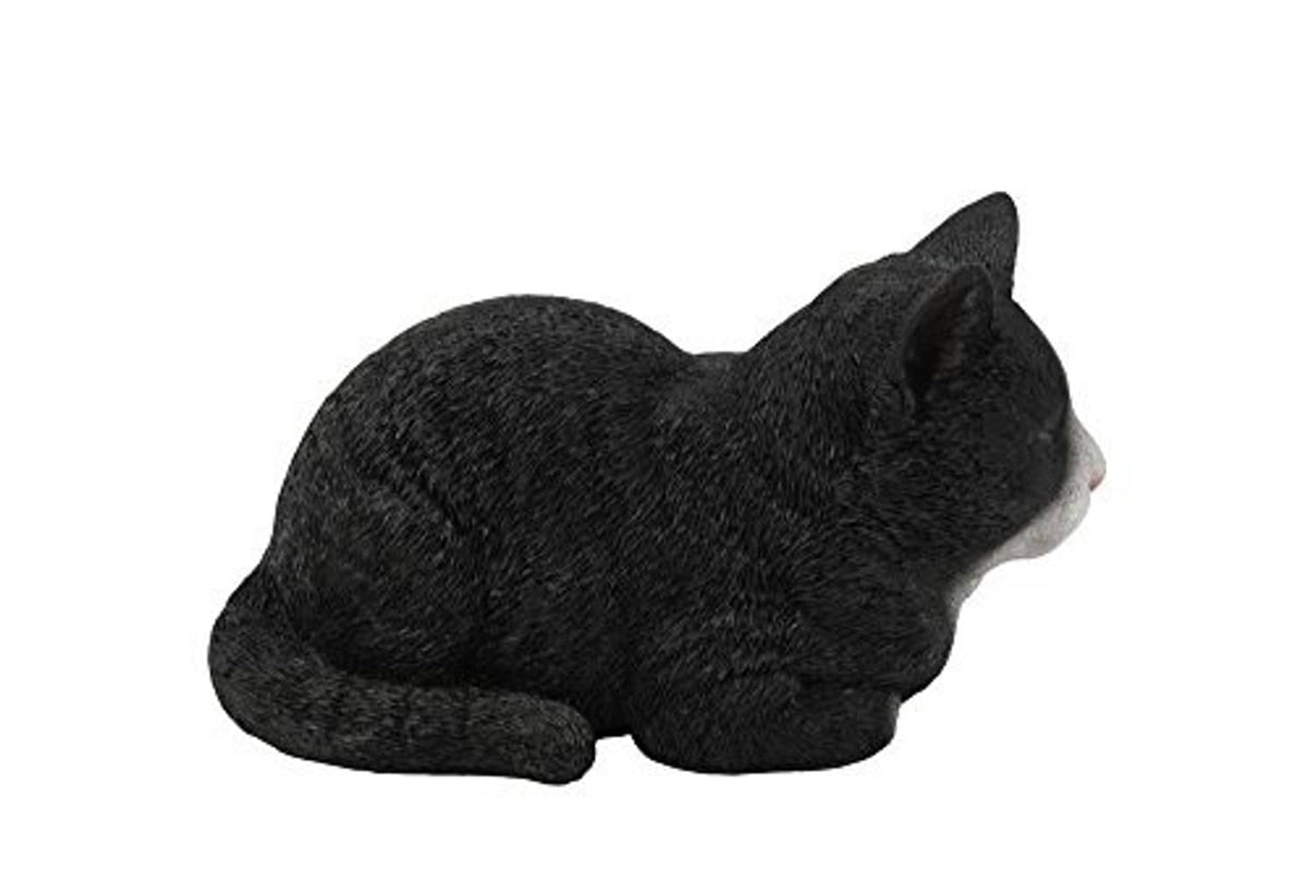 Sleeping cat statue, black with small white paw, lying curled with head up