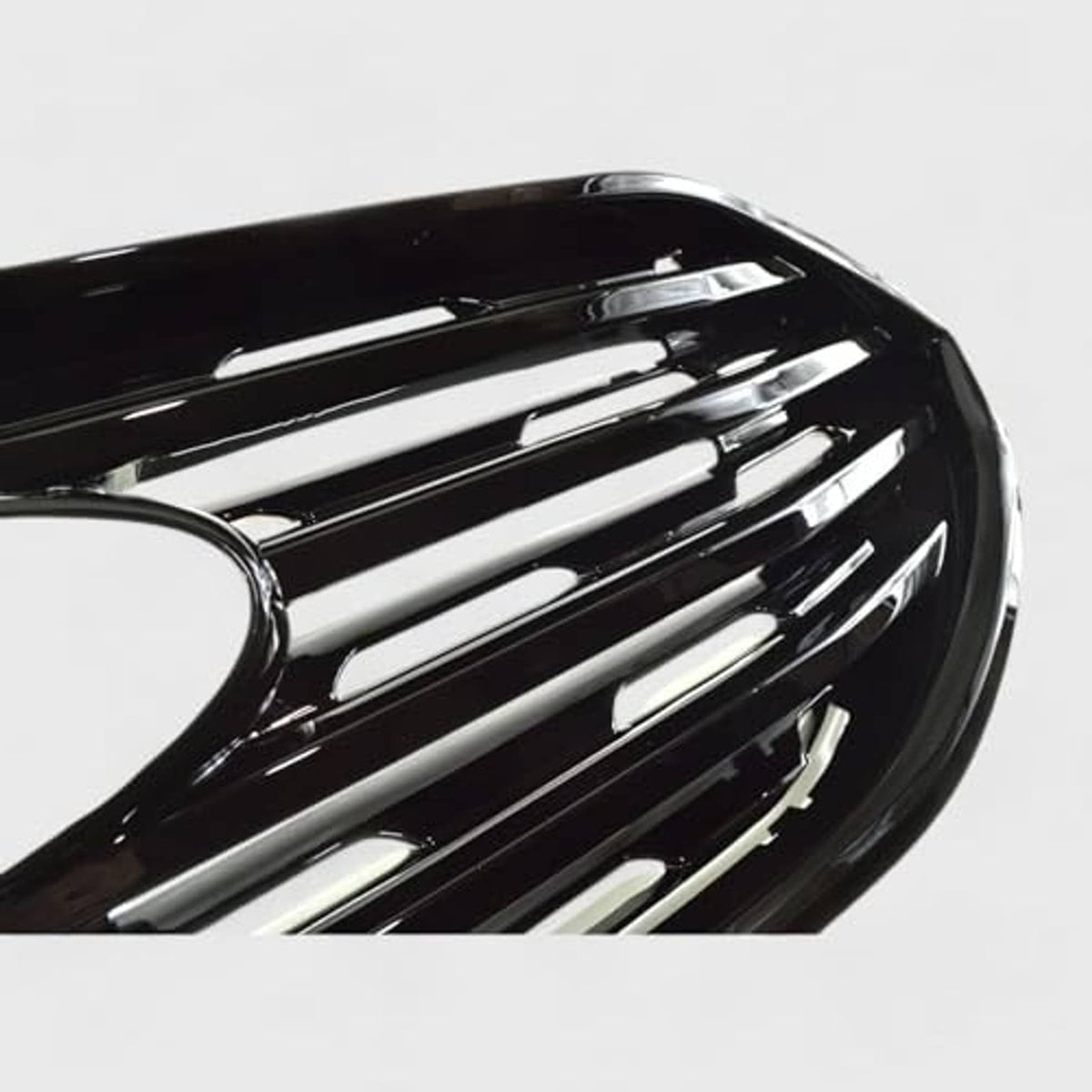 Close-up of gloss black grille overlay showing silver bar inlays and center round opening