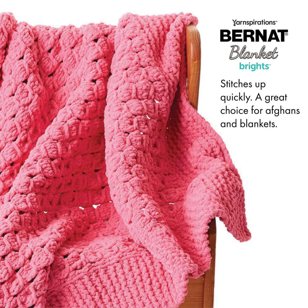 Pink chunky knitted blanket draped over a wooden chair back