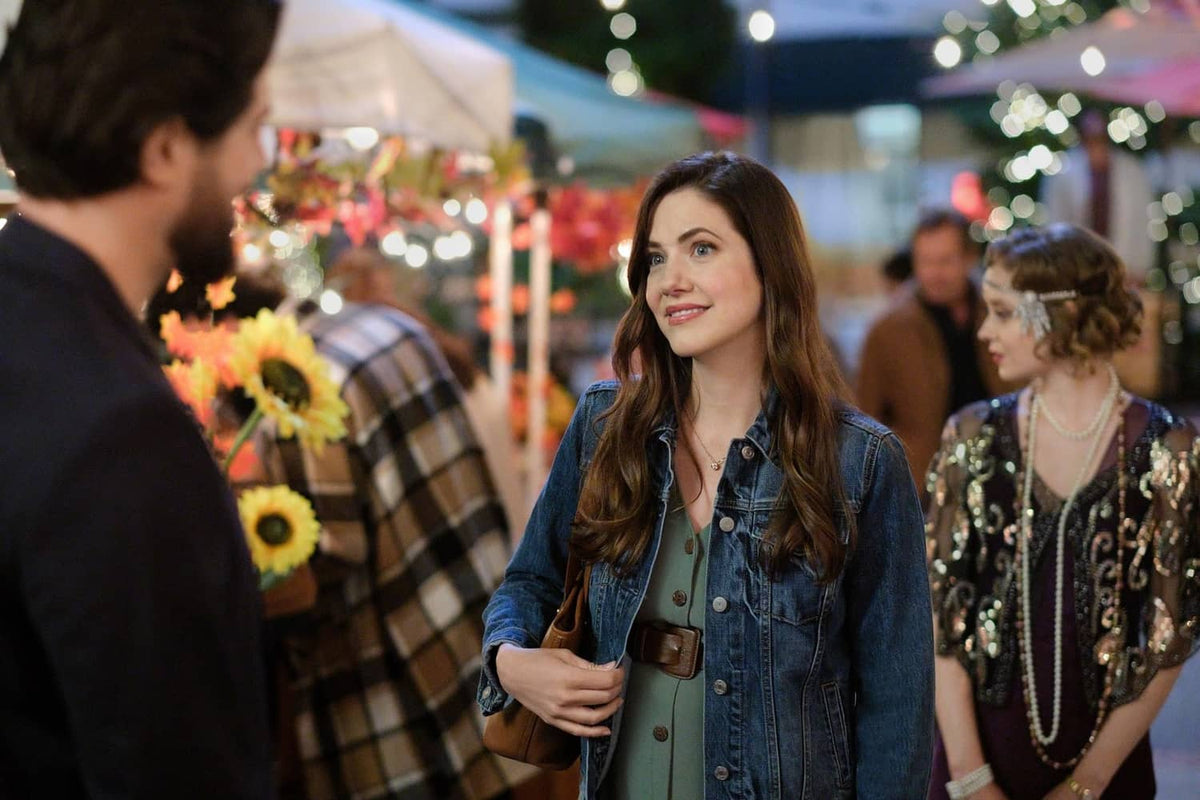Woman in blue denim jacket at an outdoor event with man and guests nearby