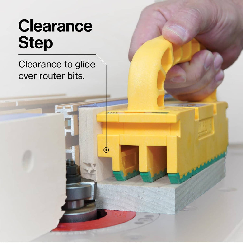 Yellow push block with arched handle guiding over router bit, green toothed base