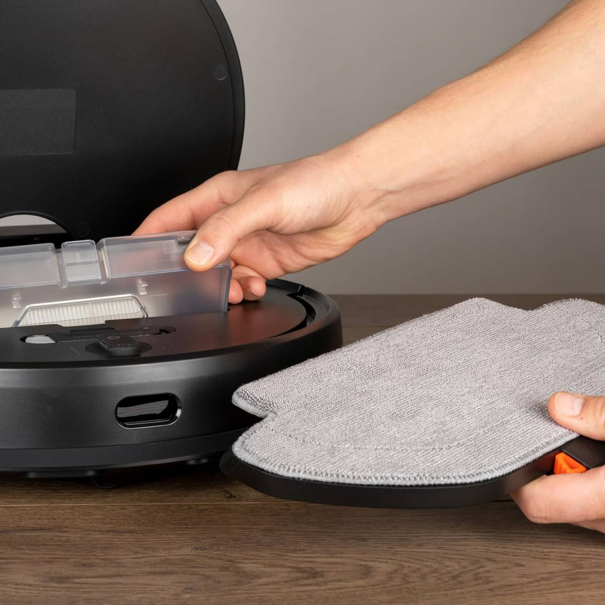 Gray cloth mop pad being attached to a robot vacuum base for mopping