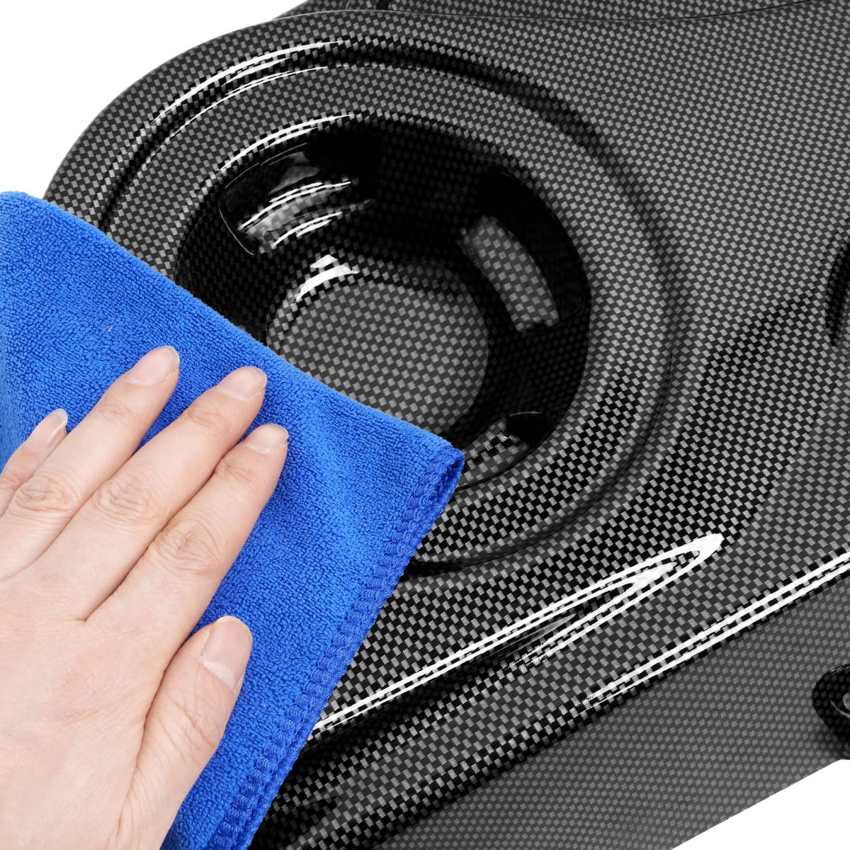 Carbon-fiber style speaker grille wiped with blue microfiber cloth, glossy black finish