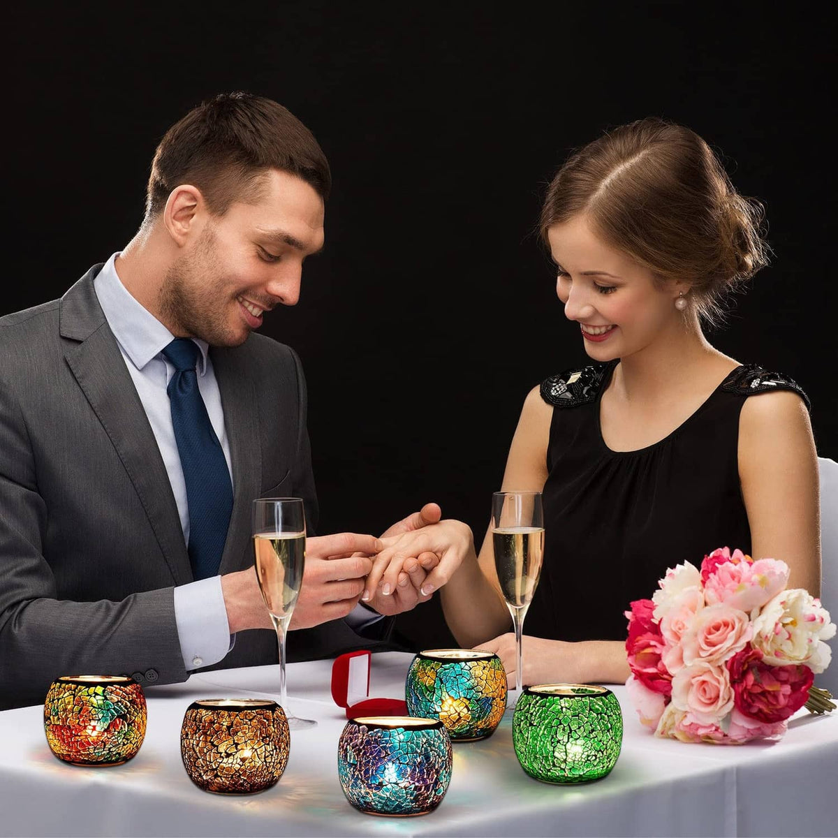 Multi-color mosaic votive candle holders on a table during a toast.