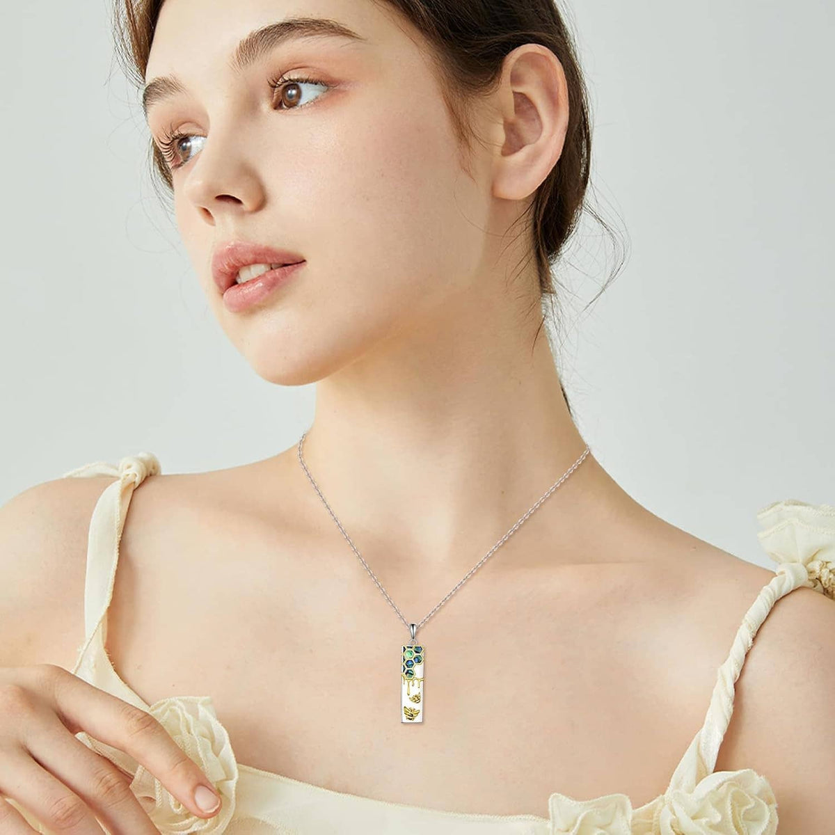 Sterling silver necklace with a vertical rectangle pendant in blue enamel and gold bee details