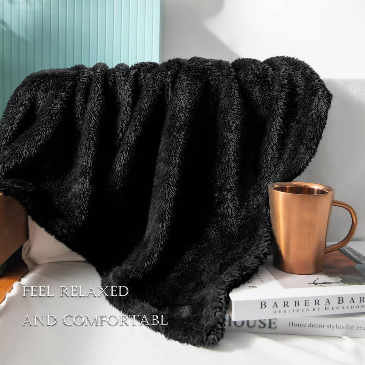 Black plush fuzzy fleece throw blanket folded on a sofa, thick shag texture